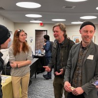 Local media employees talking to GVSU students in front of their table.